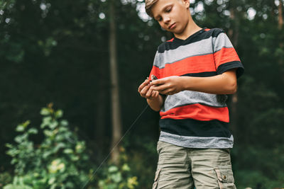 A teenage boy takes a newly caught fish off the hook. the first catch, hobbies, recreation