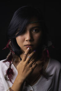 Close-up portrait of young woman against black background