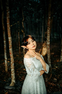 Woman standing by tree trunk in forest