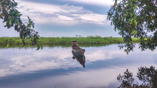 Man on boat in river against sky