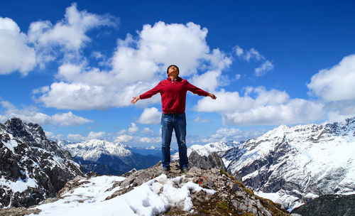 Man standing on snowcapped mountain against sky