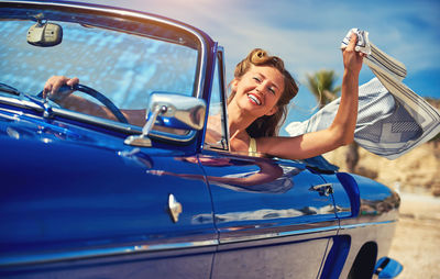 Smiling woman holding scarf while driving car