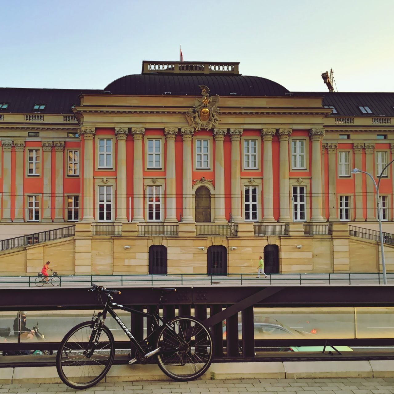 architecture, building exterior, built structure, bicycle, transportation, railing, mode of transport, window, land vehicle, city, building, sky, stationary, outdoors, parked, incidental people, travel, parking, clear sky, facade