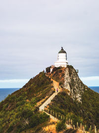 Lighthouse by sea against sky