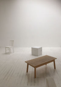 Empty chairs and table against wall