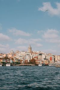 Buildings by sea against sky