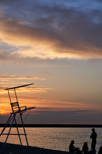 Silhouette people on beach against sky during sunset