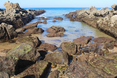 Rocks in sea against clear sky