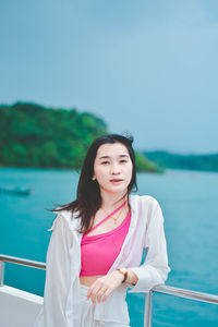 Portrait of young woman standing against sea