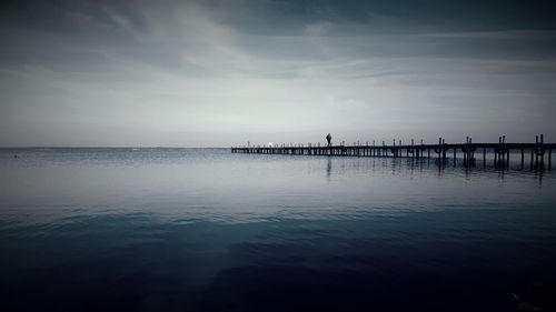 Silhouette pier over sea against sky
