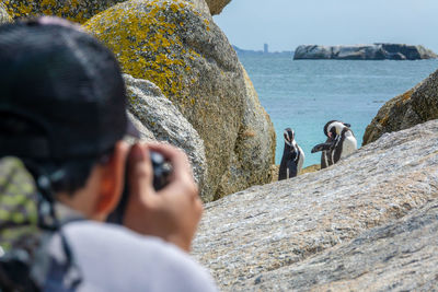 People photographing rocks on sea shore