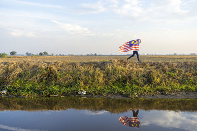 Scenic view of flag on landscape against sky