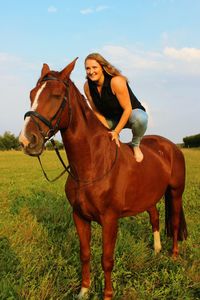 Woman riding horse on field against sky