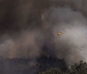 Firefighter helicopter fighting against a forest fire during day in braga, portugal.