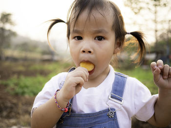 Close-up portrait of girl eating flavored ice while standing on land