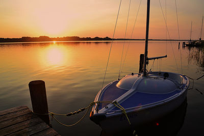 Boats moored on sea against sky during sunset