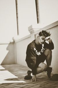 Full length of man sitting against wall