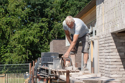 A grayhaired man saw bricks with a concrete saw of the right size for subsequent