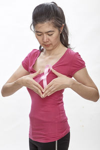 Woman wearing breast cancer awareness ribbon against white background