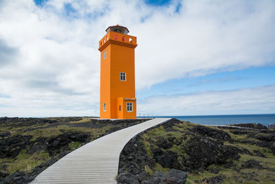 Lighthouse by sea against sky