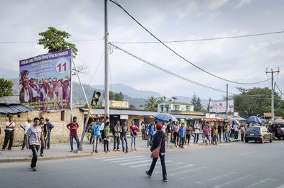 People walking on street in city against sky