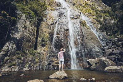 Rear view of man standing by waterfall