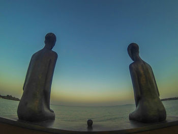 Statue of woman at beach against sky