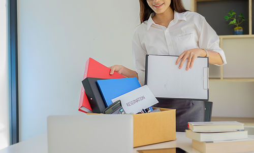 Midsection of woman packing box on desk at office after resignation