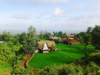 Houses on field against cloudy sky