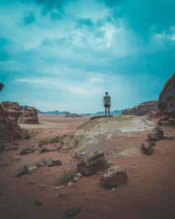 Men standing on rock against sky