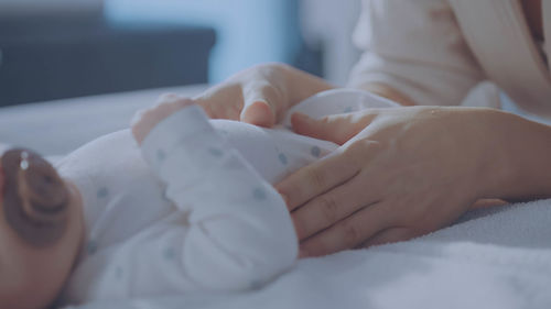 Cropped hand of woman with iv drip on bed at home