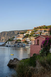 Houses by river in town against clear sky