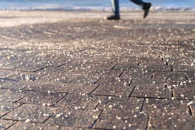 Close-up of sand on land with man walking in background