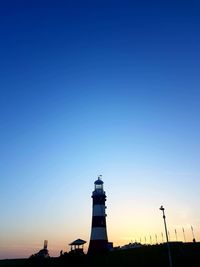 Low angle view of silhouette lighthouse against blue sky