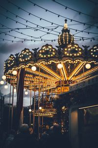 Illuminated carousel in amusement park at dusk