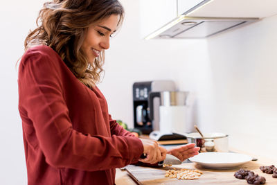 Smiling woman preparing food in kitchen at home