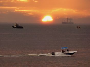 Boat sailing on sea against sky during sunset