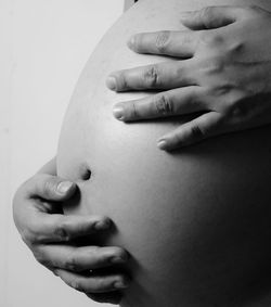 Midsection of woman touching finger against white background