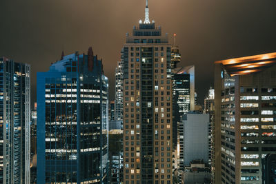 Illuminated buildings in city against sky at night