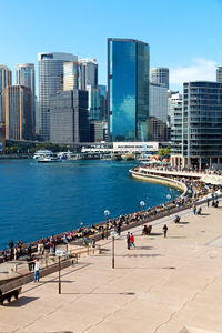 People in city by sea against clear sky