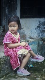 Photo of a little girl sitting wearing a red chinese ethnic dress