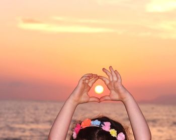 Close-up of setting sun between the hands of a child