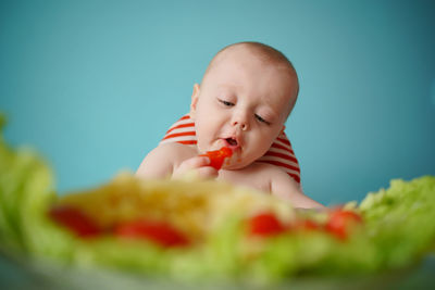 A child eats pasta with lettuce and tomatoes