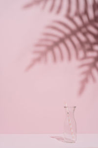 Close-up of glass container on table against wall