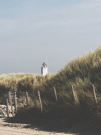 Lighthouse amidst plants and buildings against sky