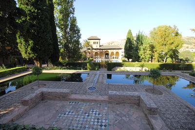 Swimming pool by trees against sky