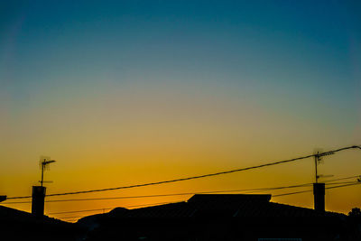 Low angle view of silhouette electricity pylon against clear sky