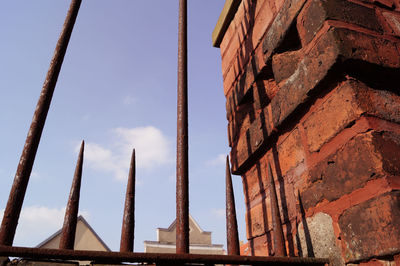 Low angle view of sharp rusty gate against sky