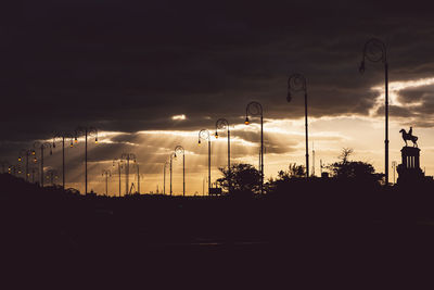 Silhouette street against sky during sunset