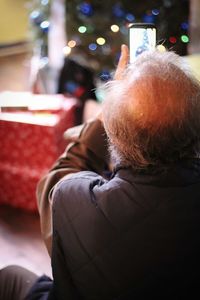 Rear view of man photographing christmas tree at home